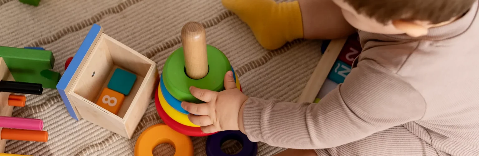 high-angle-kid-playing-with-colorful-toys-scaled